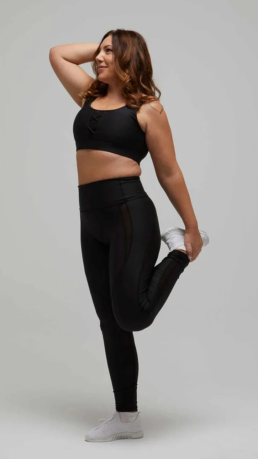 Modella in stretching con leggings neri a vita alta e top sportivo Flexivel, vista frontale