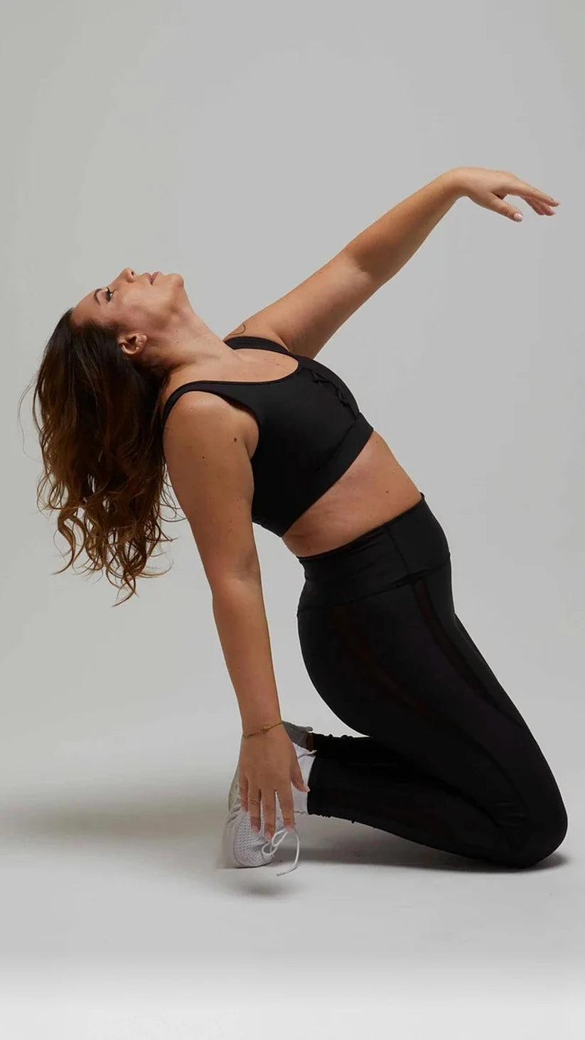 Completo sportivo nero Flexivel con leggings a vita alta e top, modella in ginocchio