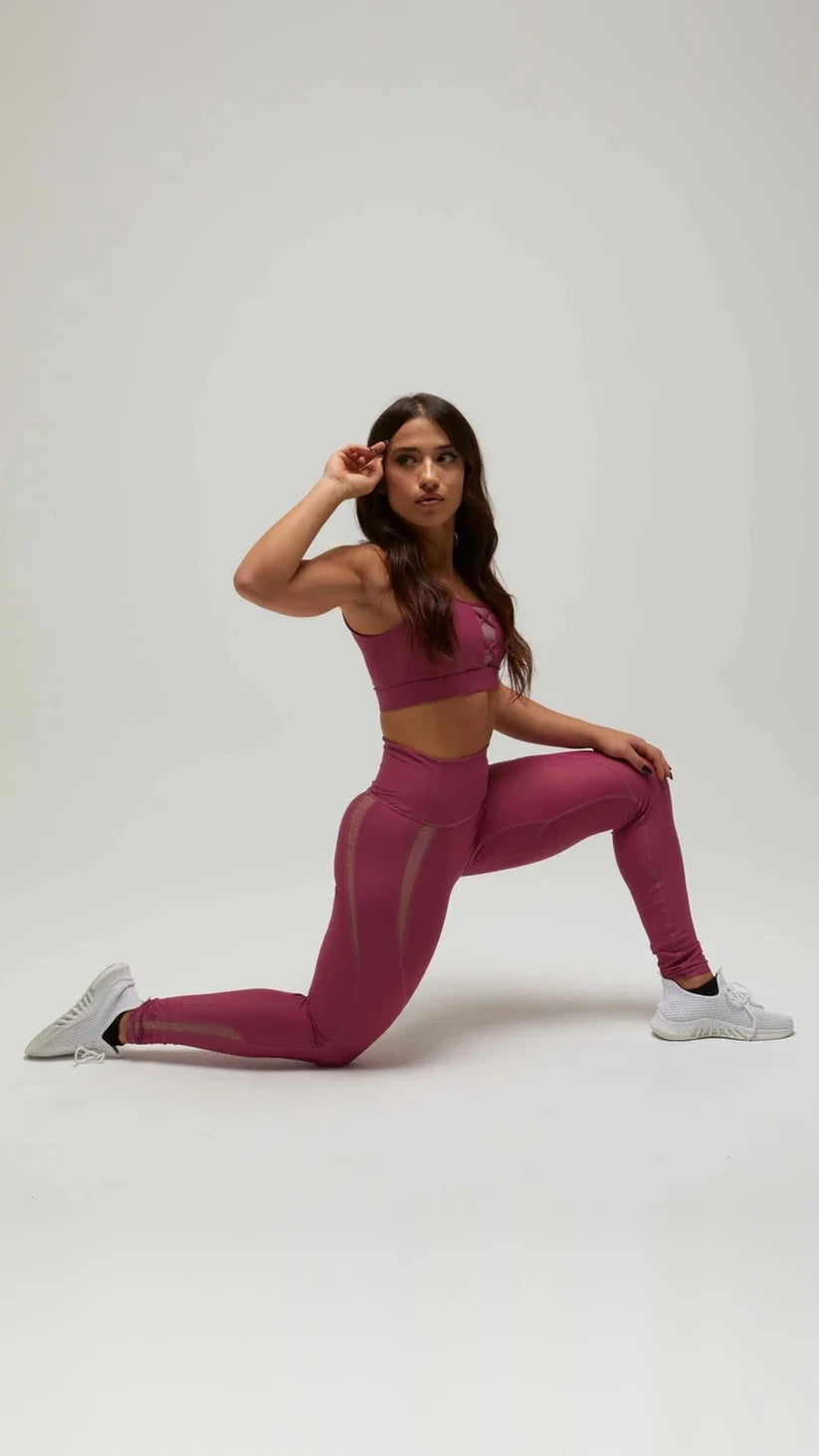 Modella in ginocchio con completo sportivo prugna Flexivel, leggings e top abbinato