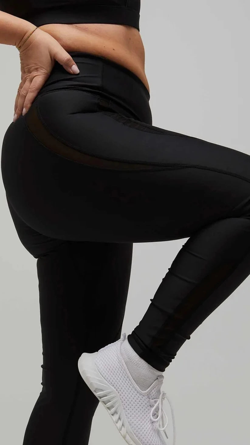 Leggings sportivi neri a vita alta Flexivel con inserti in rete, dettaglio con gamba sollevata