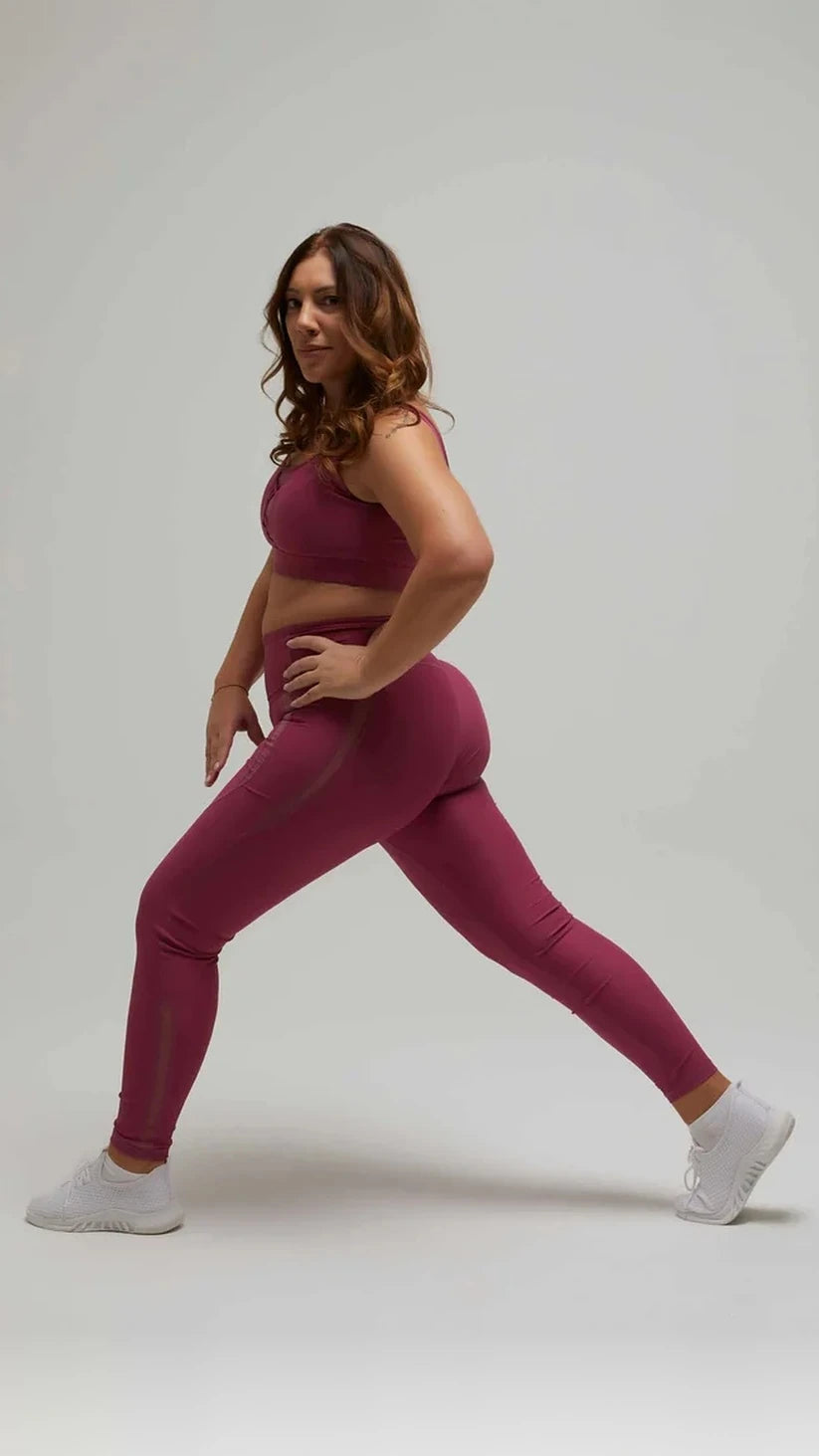 Modella in affondo con leggings prugna Flexivel con inserti in rete e top abbinato