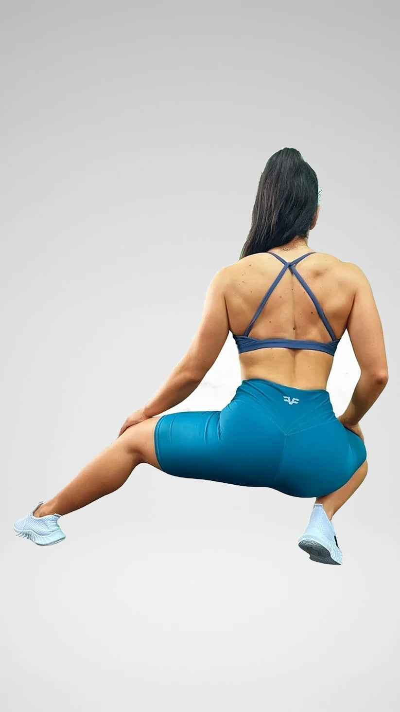 Modella in squat con shorts ciclista verde petrolio Flexivel e top incrociato, vista posteriore