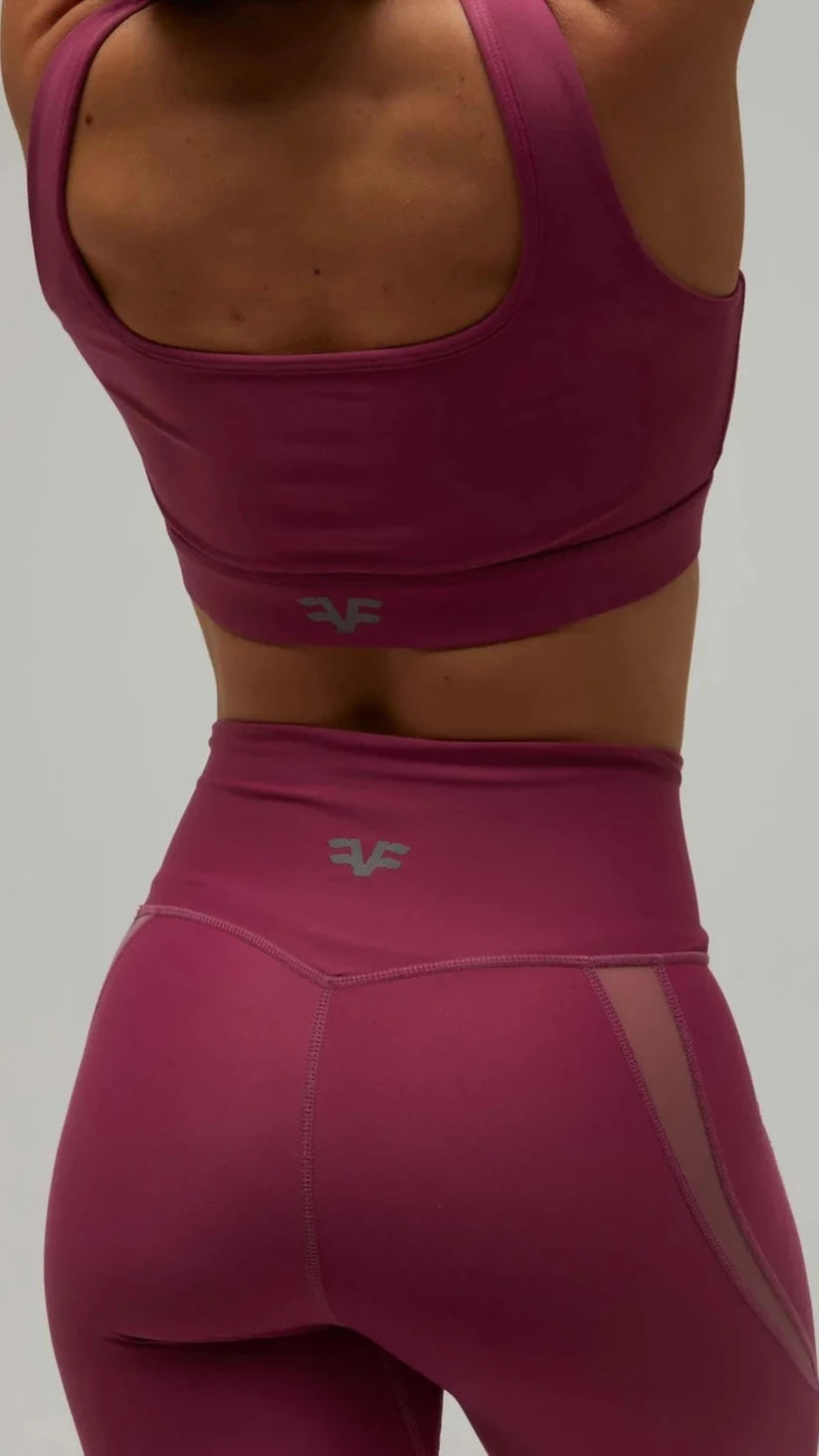 Dettaglio posteriore del top sportivo e dei leggings prugna Flexivel con logo e rete